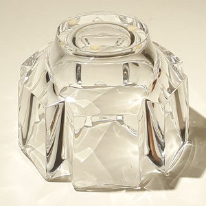 May include: A clear glass bowl with a faceted design. The bowl has a round base and a wide, open top.