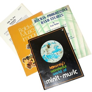 May include: A collection of four music books including Belwin Progressive Band Studies for C Flute, a Baldwin Musical Images book, a Lowrey's Wonderful World of Minit-Music book with a globe graphic, and a Baldwin Ode To Joy sheet music page.
