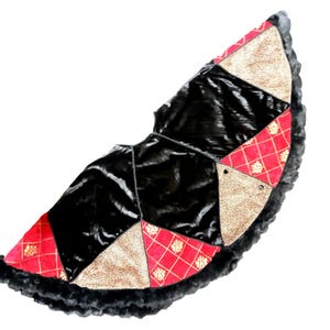 May include: A black, red and gold patchwork Christmas tree skirt with a faux fur trim.