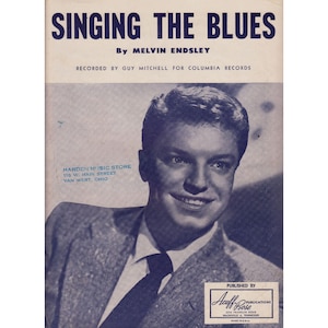 May include: A black and white photo of a man singing. The text on the sheet music reads "Singing the Blues" by Melvin Endsley. The music was recorded by Guy Mitchell for Columbia Records. The sheet music also includes the text "Harden Music Store, 118 W. Main Street, Van Wert, Ohio" and "Published by Acuff-Rose Publications, 2310 Franklin Road, Nashville 4, Tennessee".