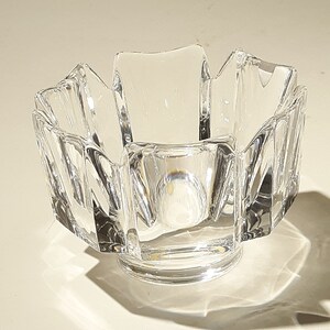 May include: A clear glass bowl with a starburst design. The bowl has a wide, shallow base and a flared rim.