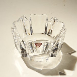 May include: A clear glass bowl with a faceted design. The bowl has a starburst shape and is made by Orrefors Sweden.