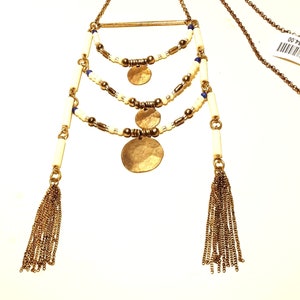 May include: A gold necklace with three layers of white and blue beads, three gold coin pendants, and two gold tassel charms.