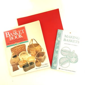 Puede incluir: Dos libros sobre cestería, uno titulado "The Basket Book" con una cubierta roja y el otro titulado "Making Baskets" con una cubierta azul. Ambos libros presentan ilustraciones de cestas.