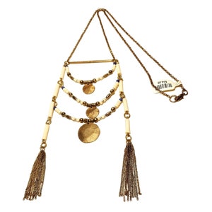 May include: A gold necklace with three tiers of white beads, gold discs, and small blue beads. The necklace has two gold tassels at the bottom and a gold chain with a clasp.