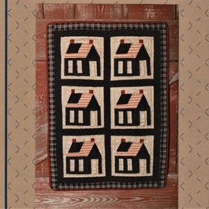 May include: A black and white quilt with a red, white, and blue pattern. The quilt features six small houses with red roofs and white stripes. The quilt is framed with a black and white checkered border.