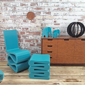 Puede incluir: Un conjunto de silla y otomana moderna en miniatura de color azul turquesa. La silla tiene un dise&ntilde;o &uacute;nico y ondulado. La otomana est&aacute; apilada con tres capas. El conjunto se muestra frente a una c&oacute;moda en miniatura con cajones y una escultura de esfera negra.
