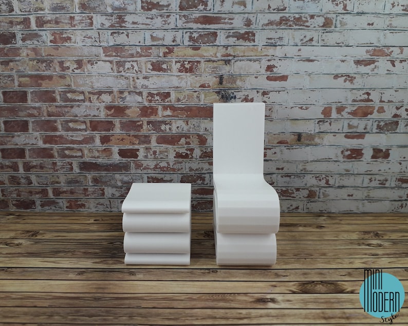 Puede incluir: Silla y mesa auxiliar blancas modernas con un dise&ntilde;o curvo. La silla y la mesa est&aacute;n frente a una pared de ladrillo y un suelo de madera.