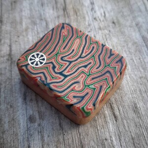 edc soapbar / worry stone with orange/black/green colors and Viking "Helm of Awe" warrior pin. Vintage Westinghouse / Maze pattern micarta