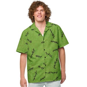May include: A green button-down shirt with a black stitch pattern. The shirt is paired with light blue shorts and white sneakers. The shirt has short sleeves and a collared neckline. The overall style is casual and summery.