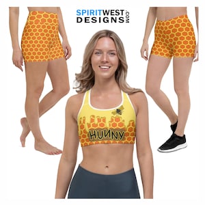 May include: A yellow and orange sports bra with a honeycomb pattern and a bee graphic. The bra has the word "Hunny" printed on it. The model is also wearing matching yellow and orange shorts with a honeycomb pattern.