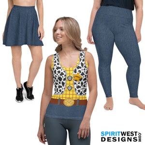 May include: A three-piece outfit inspired by the character Woody from the Toy Story franchise. The outfit includes a yellow and red plaid tank top with a black and white cow print vest, a blue denim belt with a cow skull buckle, and blue denim leggings.