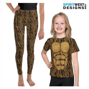 Op de afbeelding: Een bruin en gouden T-shirt met korte mouwen en een ronde hals met een harig borstontwerp en bijpassende leggings. De leggings zijn lang.