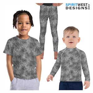 May include: Two children wearing gray and white wolf fur print clothing. The child on the left is wearing a short-sleeved t-shirt and the child on the right is wearing a long-sleeved shirt. The child in the background is wearing gray and white wolf fur print leggings.