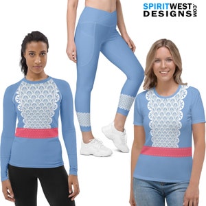 May include: Light blue athletic wear set featuring a long-sleeve shirt, leggings, and a t-shirt. Each garment has a white lace design on the front and a pink band. The leggings have a lace design at the ankles. The brand name "SPIRITWEST DESIGNS" is visible.