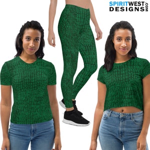 May include: Two women wearing green and black crocodile print clothing. One woman is wearing a short-sleeved t-shirt and jeans. The other woman is wearing leggings and a crop top. Both women are smiling.