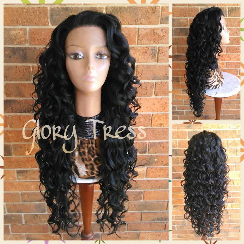 May include: A long, black, curly wig with a lace front. The wig is styled in loose, bouncy curls and is worn on a mannequin head. The mannequin is wearing a leopard print scarf.