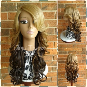 May include: A long, curly wig with blonde highlights and dark brown roots. The wig is styled with a side part and loose curls. The wig is displayed on a mannequin head with a leopard print fabric covering the head.