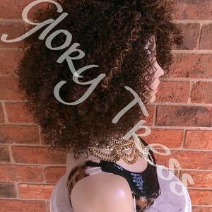 Może przedstawiać: Brązowa kręcona peruka z blond pasemkami na głowie manekina. Peruka jest ułożona w kr&oacute;tkim stylu afro.