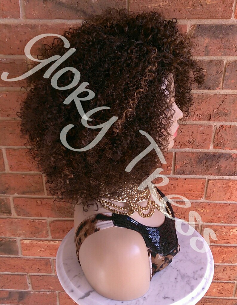 Może przedstawiać: Brązowa kręcona peruka z blond pasemkami na głowie manekina. Peruka jest ułożona w kr&oacute;tkim stylu afro.