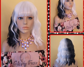 May include: A mannequin head displays a two-toned wig with white and black wavy hair. The wig has a fringe and is paired with a gold and purple jeweled necklace. The mannequin is wearing a floral off-the-shoulder top. The text "Glory Tress" is visible.