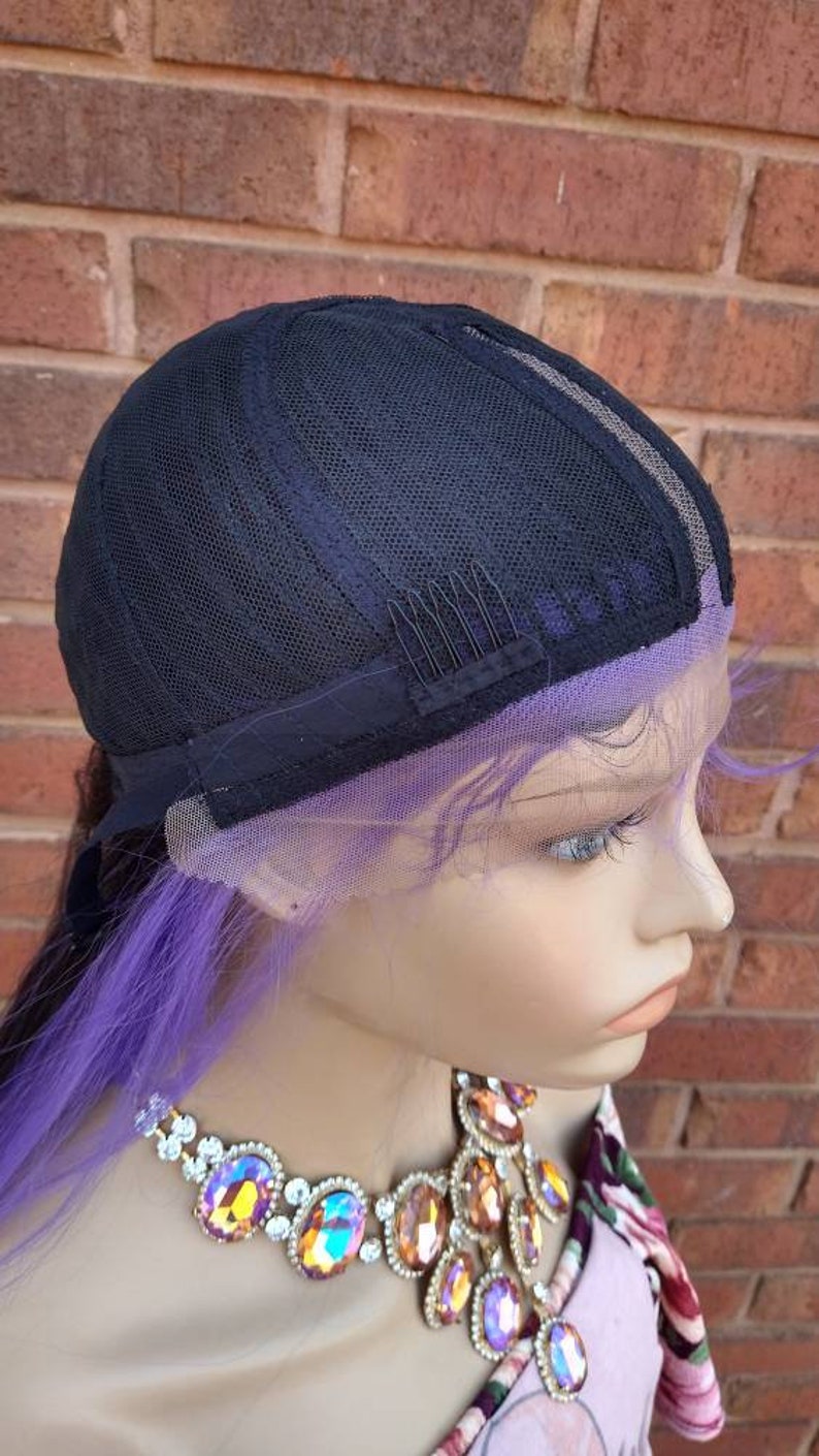 K&ouml;nnte beinhalten: Eine lila und schwarze Per&uuml;cke mit einem Spitzenfront und verstellbaren Tr&auml;gern. Die Per&uuml;cke ist in einem langen, geraden Stil gestylt. Die Per&uuml;cke befindet sich auf einem Mannequin-Kopf mit einer Juwelenkette.