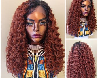 May include: A long, curly wig with a dark brown root and auburn brown ends. The wig is styled in loose, bouncy curls and is worn by a mannequin with a neutral expression.