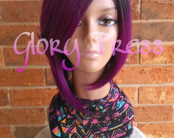 May include: A purple and black bob wig with a side part. The wig is styled with a side bang and is worn on a mannequin head. The mannequin is wearing a colorful patterned shirt.