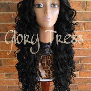 May include: A long, black, curly wig on a mannequin head. The wig is styled in loose curls and falls to the shoulders. The mannequin is wearing a leopard print top with a black sequined collar.