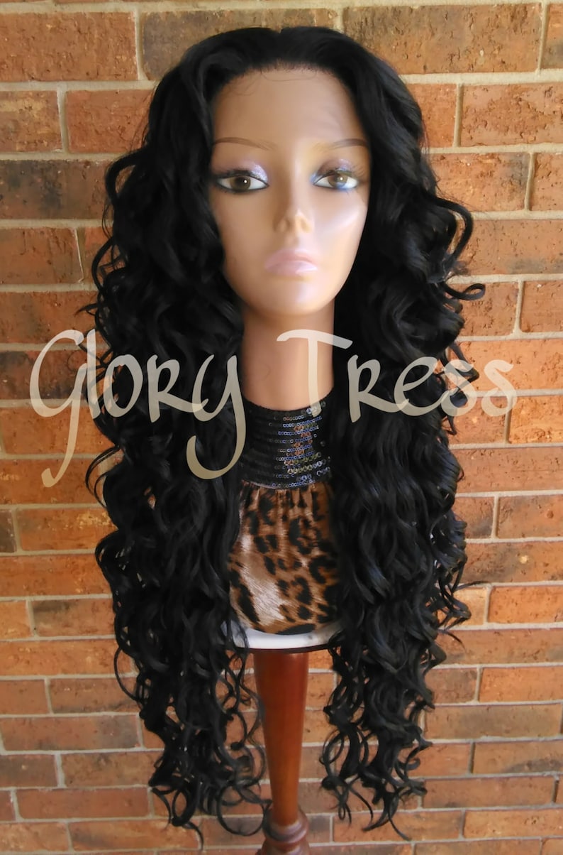 May include: A long, black, curly wig on a mannequin head. The wig is styled in loose curls and falls to the shoulders. The mannequin is wearing a leopard print top with a black sequined collar.