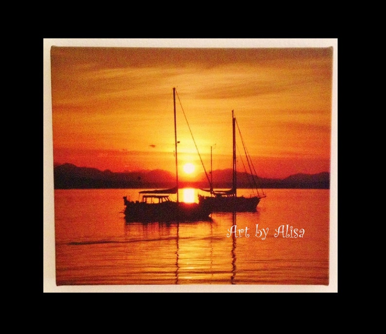 May include: Two sailboats silhouetted against a vibrant orange sunset over a calm body of water. The sky is a mix of orange, yellow, and red hues, creating a dramatic backdrop for the scene. The text "Art by Alisa" is visible in the lower right corner of the image.