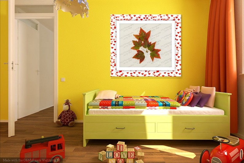 K&ouml;nnte beinhalten: Ein gelbes Kinderzimmer mit einem gr&uuml;nen Bett, einem roten Spielzeuglaster und einem gerahmten Bild von Herbstbl&auml;ttern mit einem roten Herzrand. Das Bild h&auml;ngt an einer gelben Wand. Auf dem Boden liegen auch einige bunte Bl&ouml;cke.