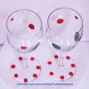 Puede incluir: Dos copas de vino de vidrio transparente con lunares rojos en el vidrio y lunares rojos en la base. Las copas est&aacute;n sobre una superficie blanca.