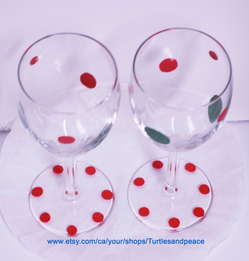 Puede incluir: Dos copas de vino de vidrio transparente con lunares rojos en el vidrio y lunares rojos en la base. Las copas est&aacute;n sobre una superficie blanca.