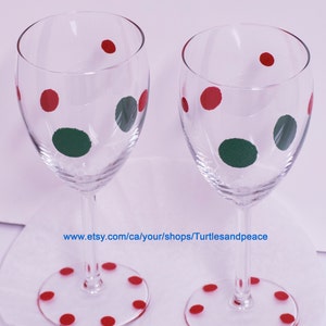 Puede incluir: Dos copas de vino de vidrio transparente con lunares rojos y verdes. Las copas est&aacute;n sobre una superficie blanca con la direcci&oacute;n del sitio web www.etsy.com/ca/your/shops/Turtlesandpeace.
