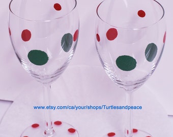 Puede incluir: Dos copas de vino de vidrio transparente con lunares rojos y verdes. Las copas están sobre una superficie blanca con la dirección del sitio web www.etsy.com/ca/your/shops/Turtlesandpeace.