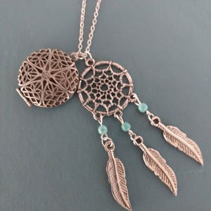 May include: Silver necklace with a locket and a dreamcatcher pendant. The dreamcatcher has three feathers and turquoise beads.
