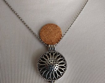 May include: A silver necklace with a round, floral-shaped pendant and a cork circle. The pendant has a delicate, intricate design.