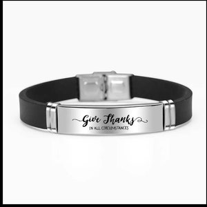 May include: A black silicone bracelet with a silver metal plate that reads "Give Thanks in all circumstances".
