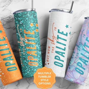 Könnte beinhalten: Vier Edelstahlbecher mit Deckeln und Strohhalmen. Jeder Becher hat ein anderes Design: orangefarbener Glitzer, türkisfarbener Glitzer, Weiß mit Text und ein pastellfarbenes geometrisches Muster. Der Text "But now the sky is Opalite" steht auf jedem Becher.