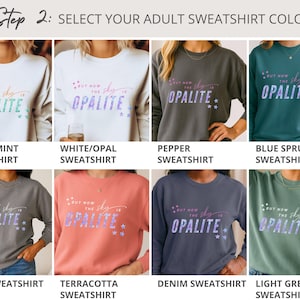 May include: Selection of adult sweatshirts in various colors, including white, grey, and blue. Each sweatshirt features the text "But now the sky is Opalite" in a decorative font with star accents. The image displays different color options.