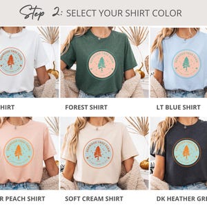 Pode incluir: Uma sele&ccedil;&atilde;o de camisetas em v&aacute;rias cores, incluindo branco, verde floresta, azul claro, p&ecirc;ssego mesclado, creme suave e cinza mesclado escuro. Cada camisa apresenta um gr&aacute;fico circular com um design de &aacute;rvore e o texto "Redwood Tree Farm". O texto "Step 2: SELECT YOUR SHIRT COLOR" est&aacute; no topo.