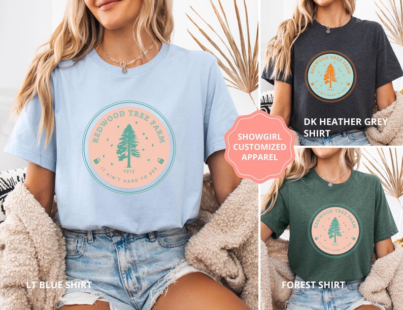 Pode incluir: Camisetas azul claro, cinza escuro e verde floresta. Cada uma apresenta um gr&aacute;fico circular com o texto "Redwood Tree Farm" e uma ilustra&ccedil;&atilde;o de &aacute;rvore. O texto "It ain't hard to see" tamb&eacute;m est&aacute; inclu&iacute;do.