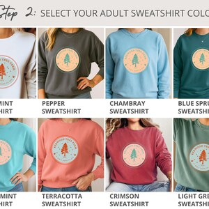 Pode incluir: Uma sele&ccedil;&atilde;o de camisolas para adultos em v&aacute;rias cores, incluindo branco, cinzento, azul e verde. Cada camisola apresenta um gr&aacute;fico circular com um desenho de &aacute;rvore e o texto "Redwood Tree Farm". A imagem mostra as op&ccedil;&otilde;es de cores dispon&iacute;veis.