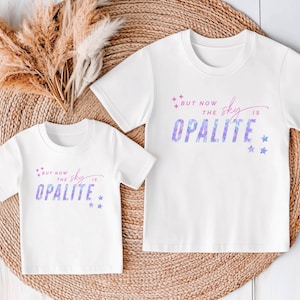 May include: Two white t-shirts with the text "BUT NOW THE SKY IS OPALITE" in a purple and blue watercolor design. The shirts have short sleeves and a crew neck. The design includes stars.