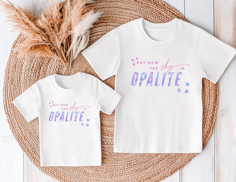 May include: Two white t-shirts with the text "BUT NOW THE SKY IS OPALITE" in a purple and blue watercolor design. The shirts have short sleeves and a crew neck. The design includes stars.