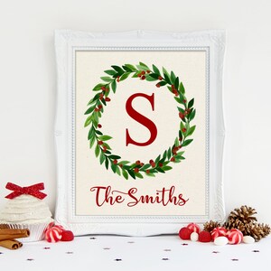 Peut inclure: Une impression encadrée avec une couronne de feuilles vertes et de baies rouges entourant une grande lettre rouge "S". Le texte "The Smiths" est écrit en dessous dans une police cursive. Le cadre est blanc.