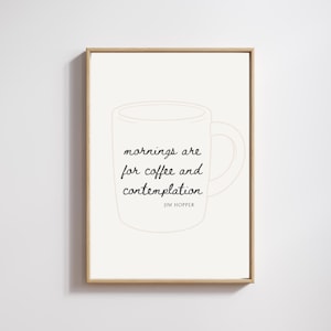 May include: A framed print with a light beige background features a sketched outline of a coffee mug. The text "mornings are for coffee and contemplation" is written in a cursive font, with "JIM HOPPER" below. The frame is a light brown color.