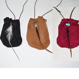 K&ouml;nnte beinhalten: Drei kleine Ledertaschen mit Kordeln und Federn. Die Taschen sind schwarz, braun und rot.