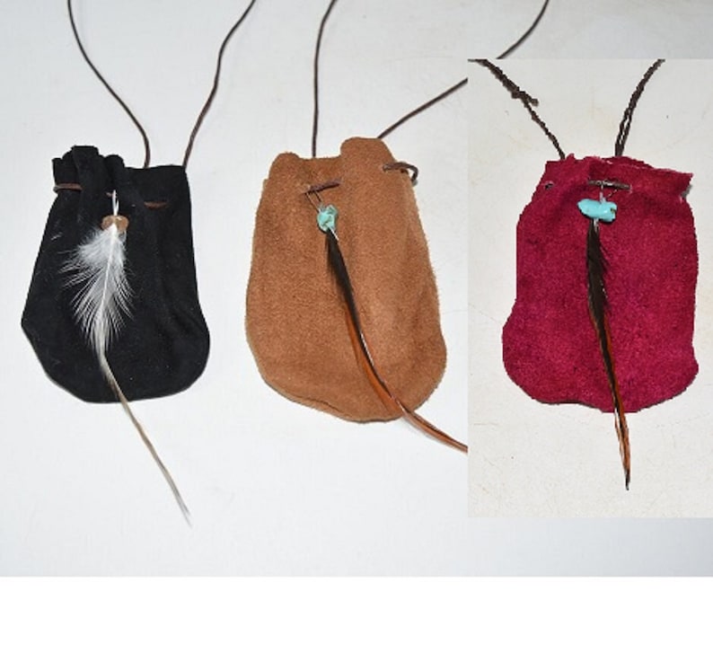 K&ouml;nnte beinhalten: Drei kleine Ledertaschen mit Kordeln und Federn. Die Taschen sind schwarz, braun und rot.